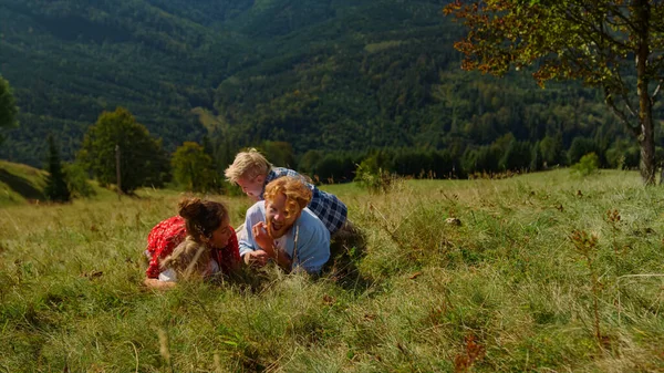 Ευτυχισμένη Οικογένεια Χαλαρώνοντας Στην Πλαγιά Του Βουνού Γρασίδι Μαζί Χαμογελαστοί — Φωτογραφία Αρχείου