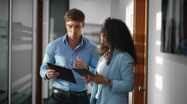 Erkek kadın meslektaşlar ofiste dijital cihaza yakın çekim yapıyorlar. Cam duvarda tabletle duran özenli insanlar. İş konuşan yaratıcı meslektaşlar. Bilgisayarda birlikte çalışan ortaklar