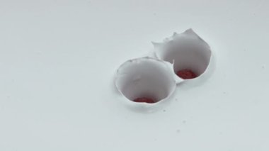 Taze yoğurdun içine düşen olgun kırmızı ahududu süper yavaş çekimde su sıçratıyor. Lezzetli vitamin meyveleri ekşi kremanın içine düştü ve ev yapımı süt tatlısını hazırladı. Sağlıklı beslenme.