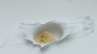 Tatlı sarı muz parçaları süper yavaş çekimde taze yoğurdun içine düştü. Sütlü tatlıya dökülen tatlı ve lezzetli meyveler. Kahvaltıda lezzetli tatlı pişiriyorum..
