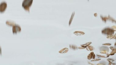 Doğal yulaf gevrekleri çok yavaş çekimde doğal yoğurdun içine düşüyor. Kahvaltı için lezzetli organik yulaf ezmesi hazırlayan mısır gevreği süt suyuna döküldü. Beslenme sağlıklı beslenme kavramı.