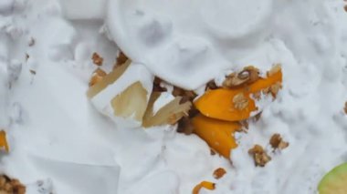 Süper yavaş çekimde taze beyaz yoğurtla lezzetli müsli hazırlıyorum. Doğal sütlü krema, sulu meyveli yulaf ezmelerine dökülüyor. Organik malzemeli sütlü tatlı..