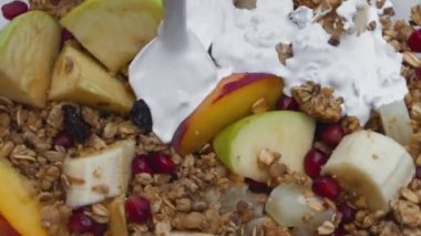 Lezzetli meyveli müsli taze doğal kremayı çok yavaş çekimde yakın çekimde dök. Lezzetli granola üzerine akmış beyaz besin yoğurdu ve şeftalili muz aromalı nar. Sağlıklı yaşam tarzı.