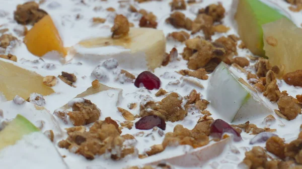 Fruit cereal milk dessert preparing with juicy apricot apple banana pineapple baked sweet granola close up. Vitamin organic ingredients dipped into creamy natural yogurt. Healthy diet nutrition.