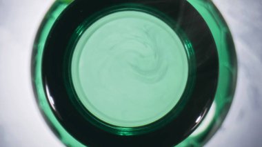 İçki şişenin üst tarafını açtı. Üstünde buhar olan filtresiz bira şişesi. Alkol, alkollü sıvı beyaz arka plan. Yeşil kabın içinde zıpzıp taze bira, yakın plan. Arpa içkisi konsepti 