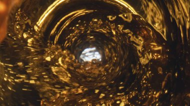 Altın likit akıntılı kadehler yakın plan. Fizzy şişelenmiş içecek doldurma cam makro yavaş çekim. Altın gibi soğuk bira bardağın içinde sallanıyor. Alkolik malt likörü konsepti 