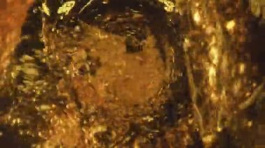 Bira fırıl fırıl dönüyor. Yakın çekim. Altın bira akıntısı çok yavaş çekimde kabarcıklar yaratıyor. Ipa içecek jeti şeffaf cam kaplamalı köpük üretiyor. Alkol içeceği konsepti 