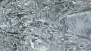 Kapanış köpüren su dokusu. Soğuk su dalgaları yavaş çekimde taze içeceklerle dönüyor. Makro kokteyl sıvısı camların içinde dönüyor. Serin yaz içeceği konsepti 