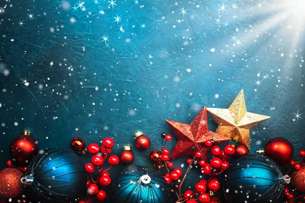 Blue Christmas or New Year background with blue Christmas balls, red berries and stars with snowflakes, top view, place for text