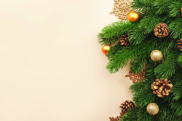 Christmas or New Year beige background with fir branches, pine cones, golden Christmas balls, bokeh lights, top view