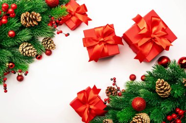 Noel ve yeni yıl arkaplanı köknar dalları, kırmızı hediye kutuları, Noel baloları ve şenlik dekorları, beyaz üst görünüm, kopyalama alanı