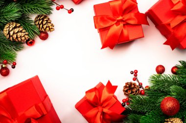 Kırmızı hediye kutuları, Noel baloları, ladin dalları, koniler ve böğürtlenlerle dolu beyaz Noel ve yeni yıl arkaplanı. Kopyalama alanı olan üst görünüm çerçevesi