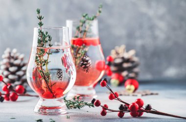 Yabanmersini, votka ve cin alkollü kokteyl, buzlu ve kekik özel bardakta. Kış aperatifi. Gri arka plan. Noel tablosu ayarları 