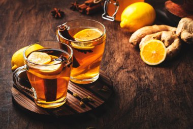 Zencefil, bal, limon ve baharatlı sıcak siyah kış çayı. Bağışıklık güçlendirici cam bardakta, ahşap masa zemininde, kopyalama alanı