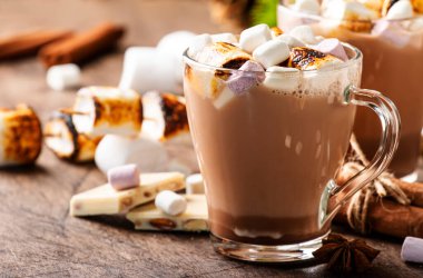 Sıcak çikolata içeceği, cam bardaklarda kızarmış marşmelov ve ahşap masada kış süsü. Sıcak Noel ve Yeni Yıl tatili kavramı