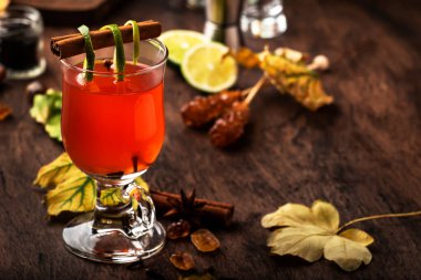 Sıcak punç, içki, kış ılık kokteyli koyu rom, porto şarabı, bal, limon suyu, çay, tarçın ve karanfiller sonbahar dekorasyonunda eski ahşap arka planda. 