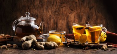 Zencefil, bal, limon ve baharatlı sıcak siyah kış çayı. Bağışıklık güçlendirici cam bardakta, ahşap masa zemininde, kopyalama alanı