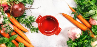 Taze bahar kökü sebzeleri, baharatlı otlar ve kırmızı tava. Sağlıklı yemekler, yemek pişirme konsepti. Kopya alanı olan gri masa arkaplanı. Üst görünüm