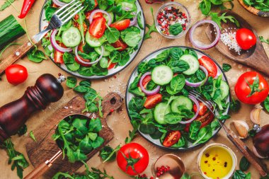 Yeşil ıspanaklı sebze salatası, kırmızı domates, salatalık, mısır salatası ve soğan. Sağlıklı vejetaryen yemeği. Taş mutfak masası arka planı. Üst görünüm