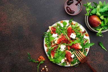 İncirli yaz salatası, beyaz peynir, ceviz, pazı ve roka reçel soslu kahverengi arka plan, üst manzara, kopyalama alanı