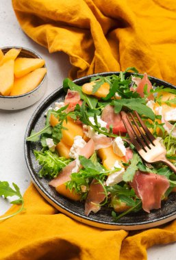 Kavun salatası kavun, prosciutto, yumuşak peynir ve roka beyaz masa arkasında, üst görünümde, kopyalama alanı