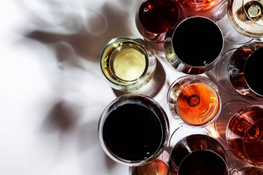 Kırmızı, beyaz, gözlüklü, beyaz arka planda çeşitli gül şarapları, üst manzara. Şarap barı, dükkan, şaraphane, açık hava şarap tatma konsepti. Sert ışık ve sert gölgeler