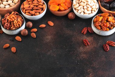 Fındık ve kurutulmuş meyve. Sağlıklı atıştırmalıklar. Kurutulmuş kayısı, incir, kuru üzüm, ceviz, ceviz, fındık, badem ve diğerleri. Kahverengi arkaplan
