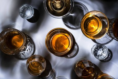 Sert içkiler, içkiler ve bardaklarda damıtılıyor: konyak, grappa, votka, viski ve çeşitli içecekler. Sert ışık ve sert gölgelerle beyaz arkaplan
