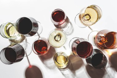 Kırmızı, beyaz, gözlüklü, beyaz arka planda çeşitli gül şarapları, üst manzara. Şarap barı, dükkan, şaraphane, açık hava şarap tatma konsepti. Sert ışık ve sert gölgeler