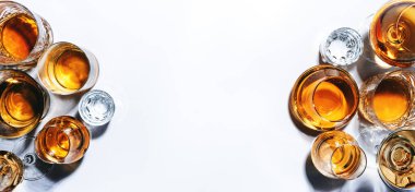 Sert alkollü içecekler, sert içkiler, bardaklarda içki ve damıtma: votka, konyak, viski ve diğer şeyler. Beyaz arka plan. Sert ışık, boşluğu kopyala