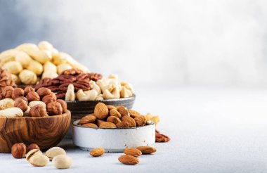 Fındıklar kaselerde. Fındık, fındık, ceviz, fındık, badem ve diğerleri. Gri masa arkaplanında sağlıklı yiyecek karışımı, kopyalama alanı