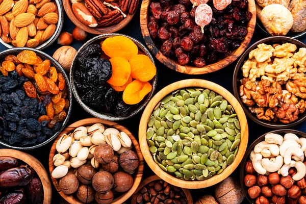 Nuts and dried fruits in assortment. Dry apricots, figs, raisins, walnuts, almonds and other. Blue table background, top view, copy space