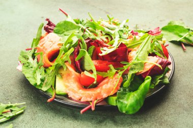 Avokado, pancar yaprağı, radicchio, domates, keto ve düşük karbonhidrat diyeti için limon ve zeytinyağı soslu taze somon salatası. Paslı yeşil arkaplan, üst görünüm, kopyalama alanı