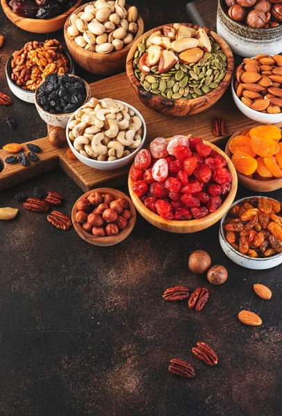 Dried fruits nuts in bowls set. Dry apricots, figs, raisins, walnuts, almonds and other. Healthy nutritious snacks. Brown table background, copy space