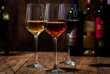 Ahşap zemin üzerinde kırmızı, beyaz ve gül şarabı ve şarap şişeleri koleksiyonu, kopyalama alanı