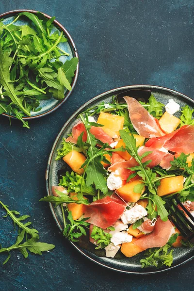 Kavunlu yaz salatası, prosciutto, beyaz peynir ve roka mavi masa arka planında, üst manzara, kopyalama alanı