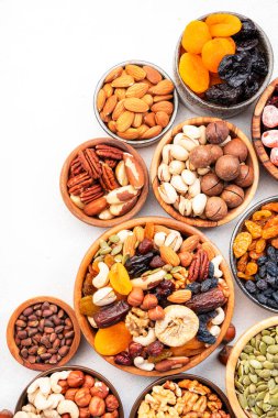Kavanozda kurutulmuş fındık. Kuru kayısılar, incirler, kuru üzümler, cevizler, bademler ve diğerleri. Sağlıklı besleyici atıştırmalıklar. Beyaz tablo arkaplanı, üst görünüm, kopyalama alanı