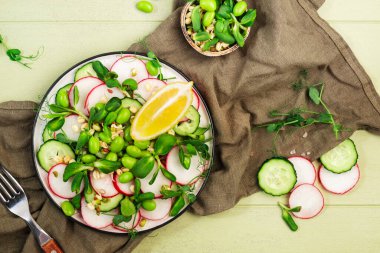 Turplu salata tabağı, salatalık, bezelye, ayçiçeği, soya ve fasulye filizi, edamame ve keten tohumu. Vejetaryen vejetaryen sağlıklı yiyecekler. Üst manzara, yeşil mutfak masası. 