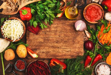 Sağlıklı yemek pişirmek ve ahşap mutfak masasında tahta kesmek için çeşitli pişirilmemiş sebzeler, otlar ve baharatlar. Vejetaryen lahanası, pancar kökü, domates çorbası. Vejetaryen, dengeli, diyet yemekleri. 