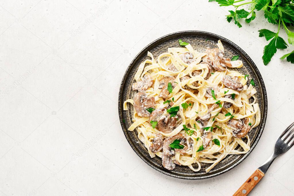 Mushroom Tagliatelle Pasta with parmesan cheese and cream sauce on white background, top view. Prepared italian pasta with champignon on plate 