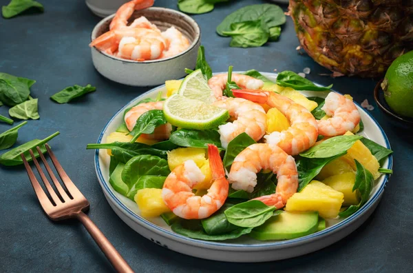 Pineapple salad with shrimps, spinach, avocado and lime on blue stone kitchen table, top view. Healthy eating, balanced, clean diet food, weight loss concept