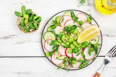 Turplu taze salata, salatalık, bezelye, ayçiçeği, soya ve fasulye filizi, edamame ve keten tohumu. Vejetaryen vejetaryen sağlıklı yiyecekler. Üst manzara, eski beyaz mutfak masası. 