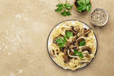 Tabakta şampiyon mantarlı lezzetli makarna bej taştan mutfak masası arka planında maydanoz, üst manzara. Sağlıklı vejetaryen yemekleri ve yemekleri. İtalyan gıda konsepti
