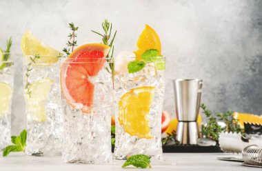 Cin tonik limon kokteylleri hazır. Limonlu, limonlu, greyfurtlu, portakallı, gazozlu ve viski bardaklı alkollü içecekler, gri arka plan. Yaz kokteyli partisi