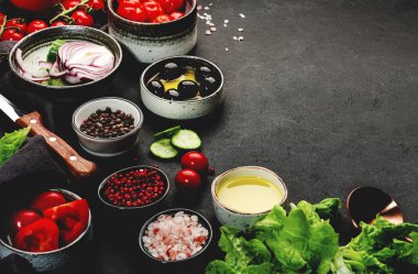 Yunan salatası pişirmek için sebze, zeytin, yağ ve malzeme beyaz peynir, kiraz domatesi, kırmızı salatalık ve kırmızı soğan, sağlıklı vejetaryen Akdeniz diyeti yiyecekler, düşük kalorili yiyecekler. Siyah taş arkaplan, üst görünüm