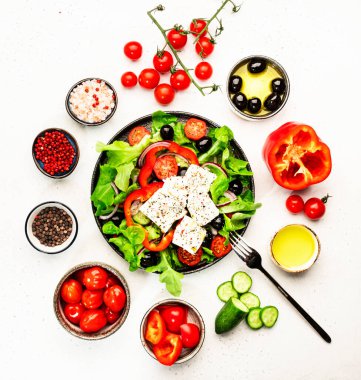 Greek salad with feta cheese, olives, cherry tomato, paprika, cucumber and red onion, healthy vegeterian mediterranean diet food, low calories eating. White stone background, top view clipart