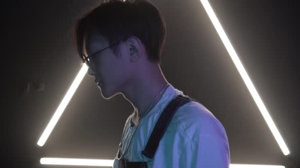 Молодой стильный азиат на неоновом светлом фоне. Привлекательный корейский или китайский мужчина в неоновом свете — стоковое видео
