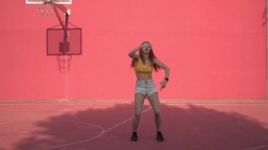 Açık havada hip hop dansı yapan genç seksi kadın. Modern yaratıcı gençlik. Kırmızı duvarın arkasında dans eden aktif bir kadın.