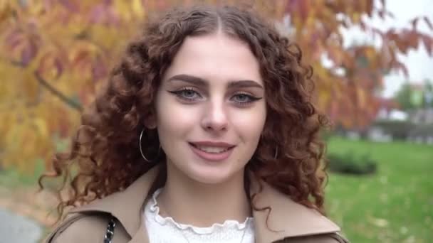 Portrait d'une jeune belle femme bouclée sur fond d'automne à l'extérieur — Video