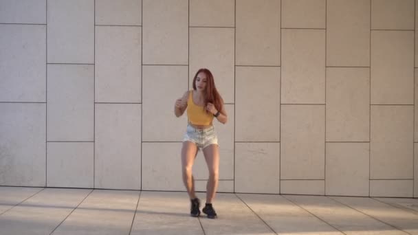 Молода руда жінка танцює хіп-хоп на відкритому повітрі. Молодіжний спосіб життя, жінка танцює на вулиці. Приваблива сексуальна жінка танцівниця — стокове відео